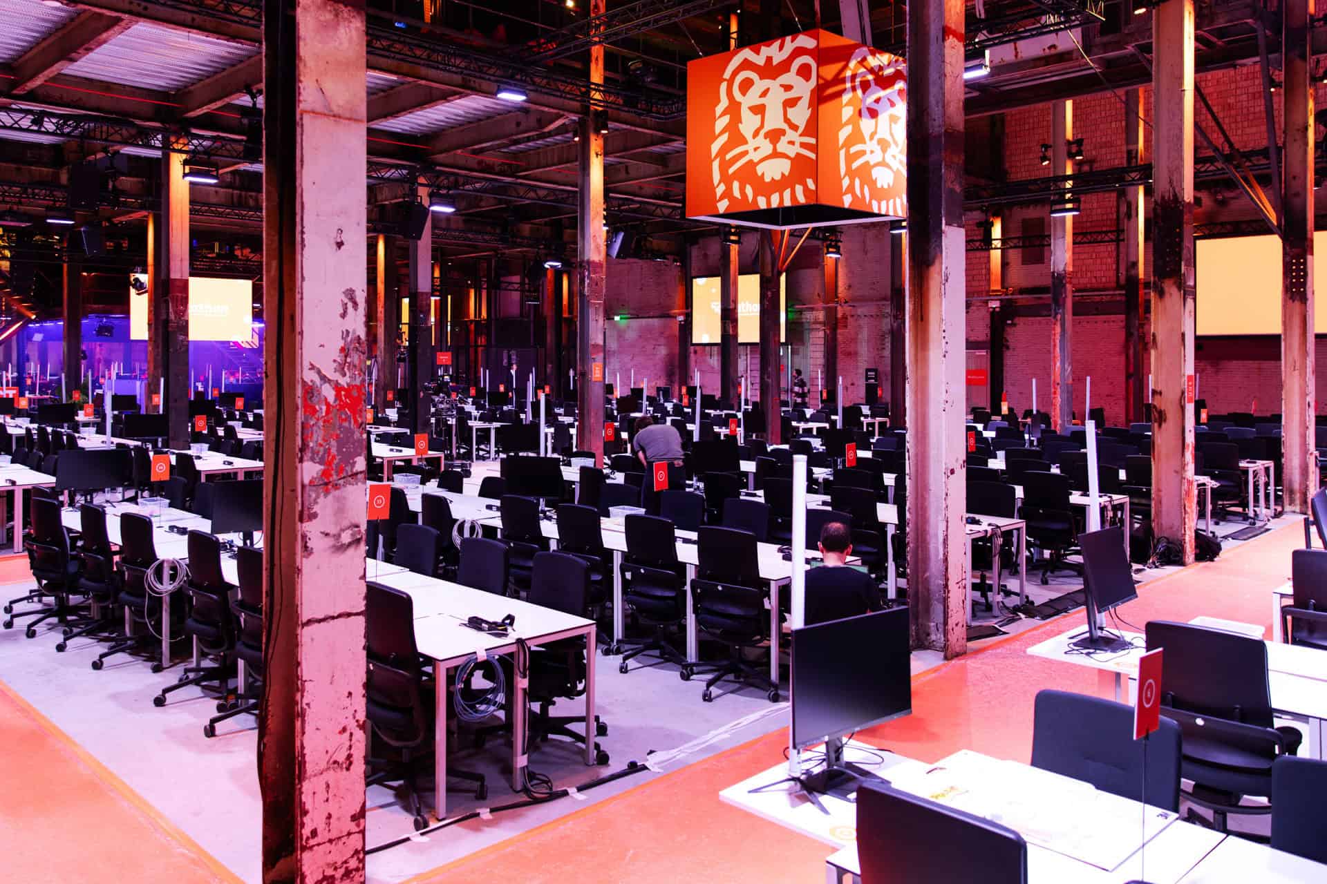 Hackathon locatie met werkstations en grote schermen voor tech-innovatie en samenwerking.