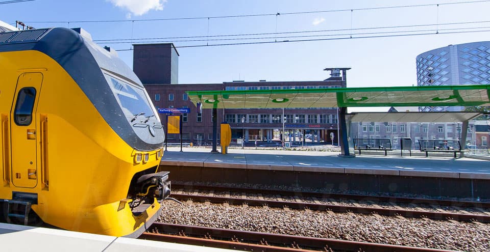 Reiziger wacht op trein op het station, klaar voor vertrek.